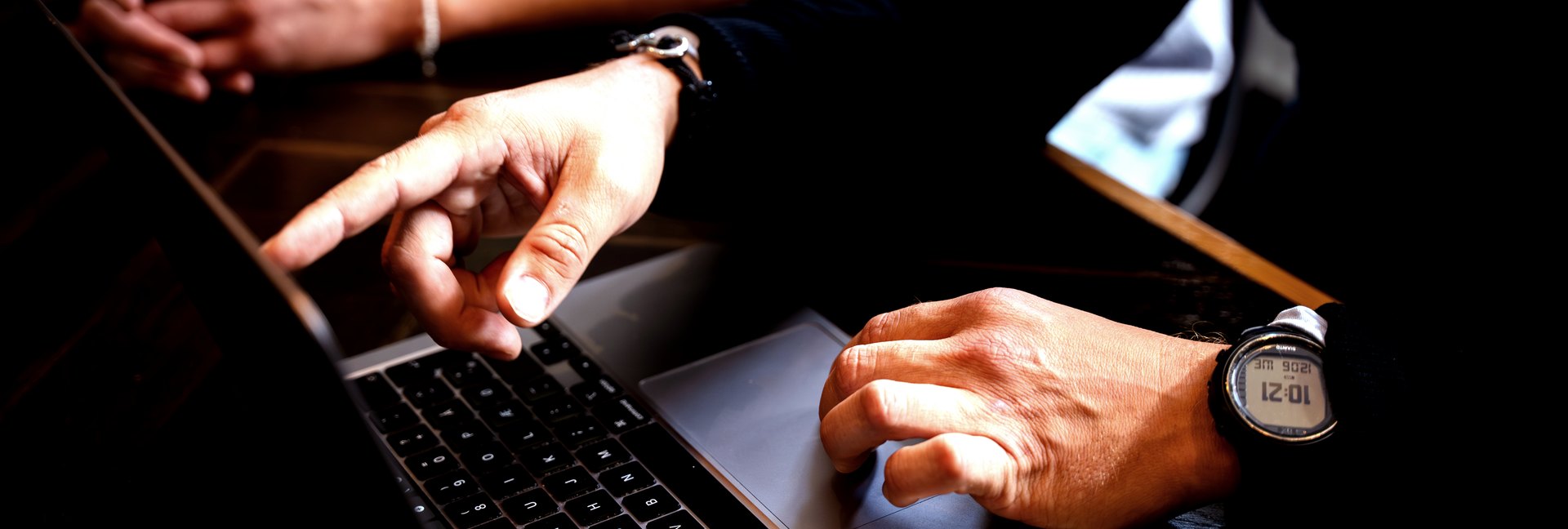 Nærbillede af hænder ved en bærbar computer under en arbejdssession, den ene peger på skærmen.